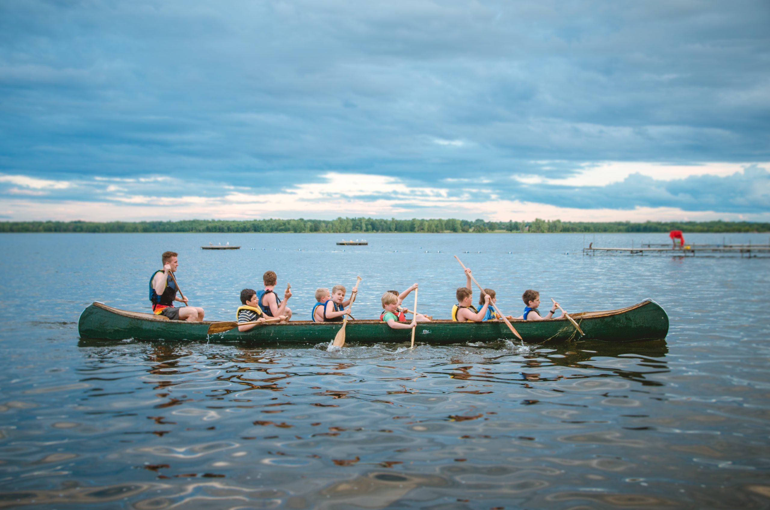A counselor and a group of boys rowing in a kayak