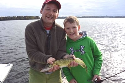 Father and son holding a fish on the lake