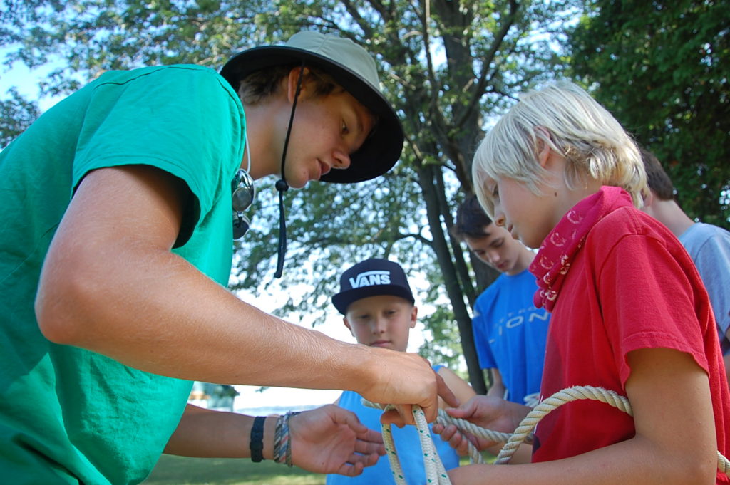 Counselor and campers tying rope