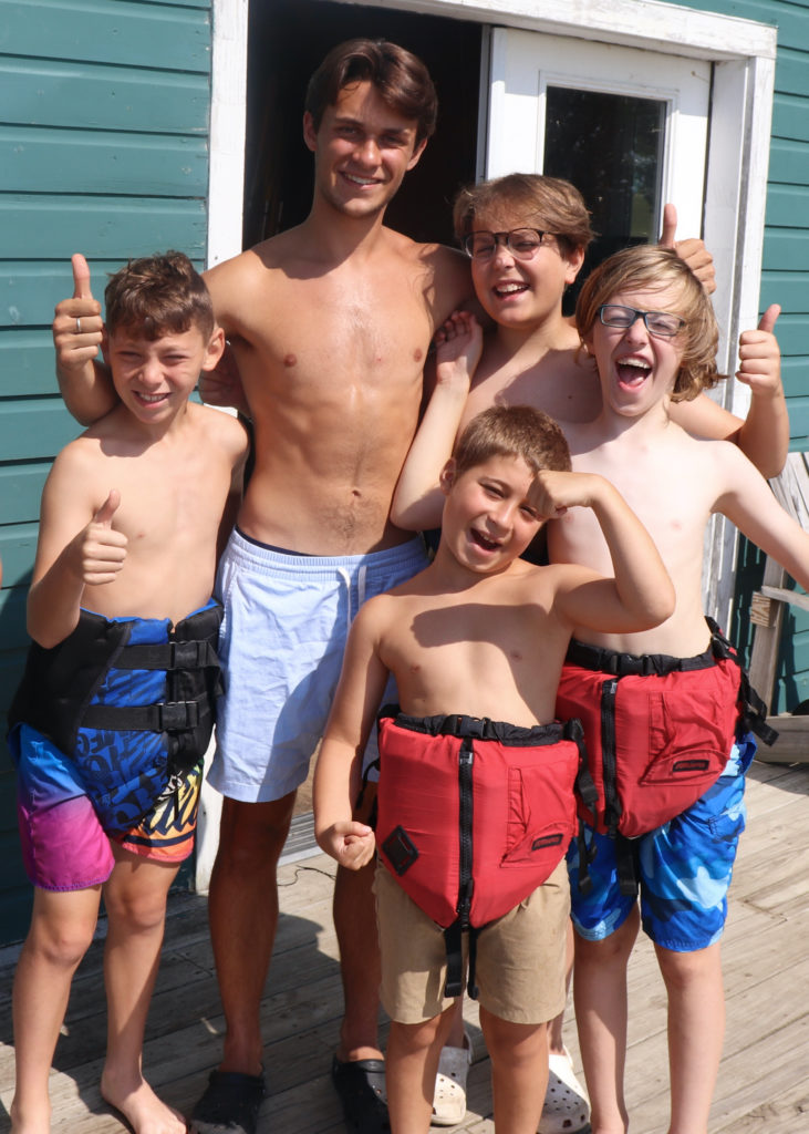 Campers and their counselor giving the thumbs up while wearing life vests like pants