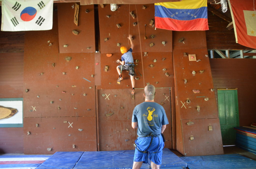 Camper climbing up an indoor rock wall
