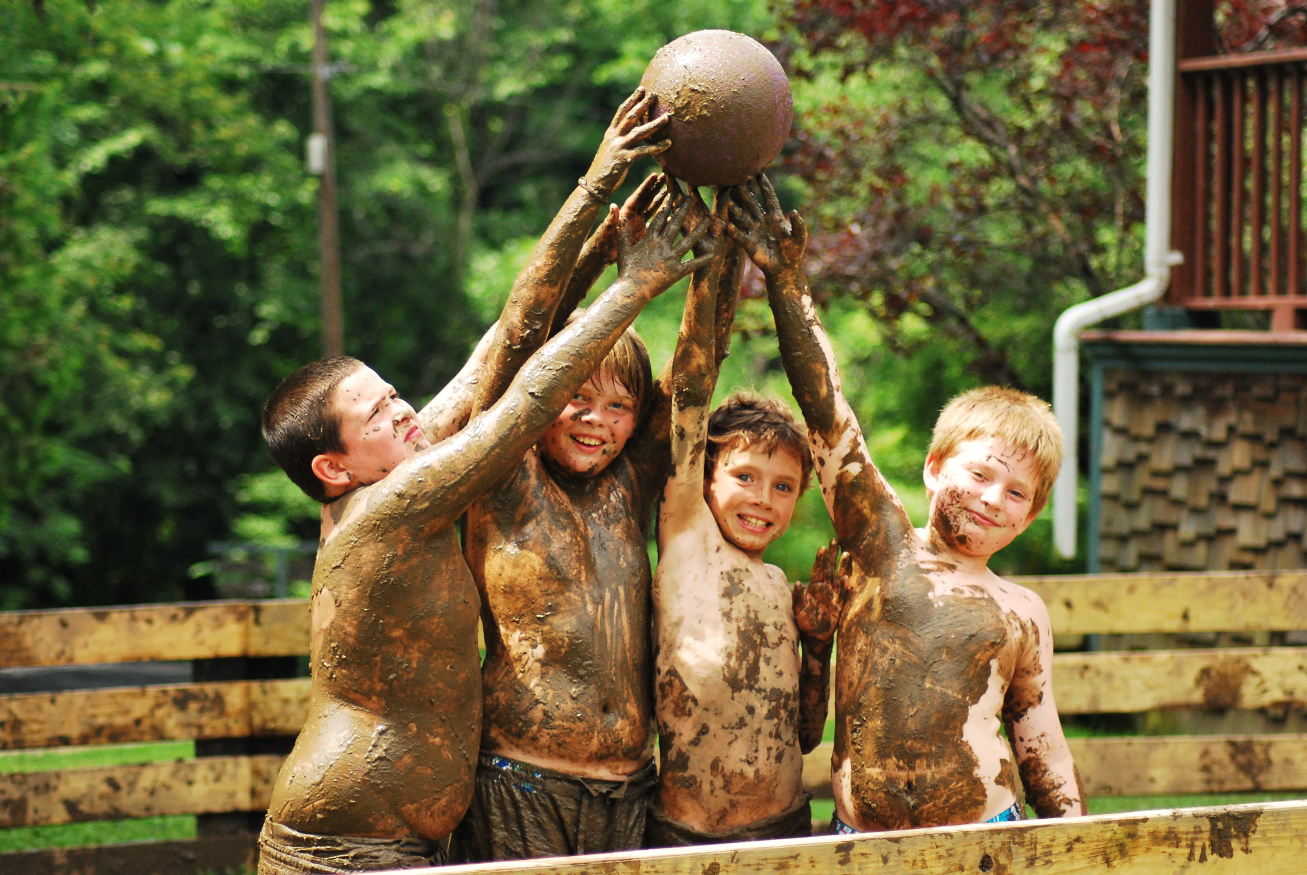 Muddy campers holding up a ball
