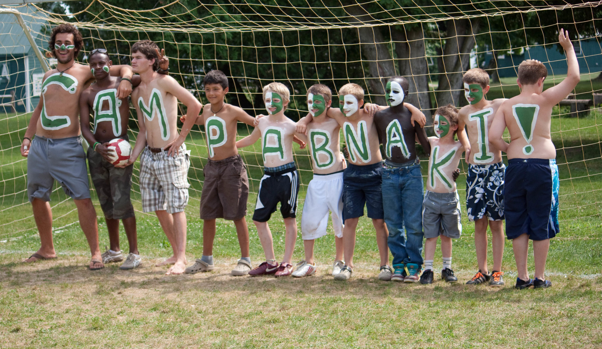 Campers with letters spelling Camp Abnaki painted on their chests in front of a soccer goal